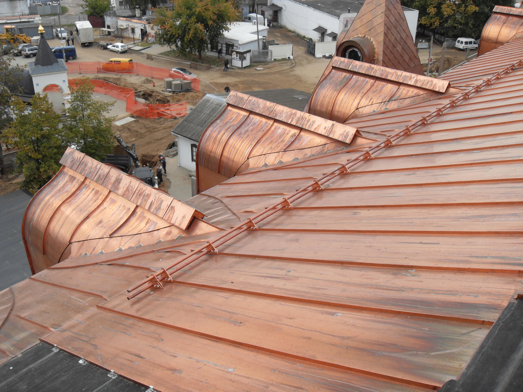 Freshly installed copper roof with curved bellcast eaves and standing seam panels