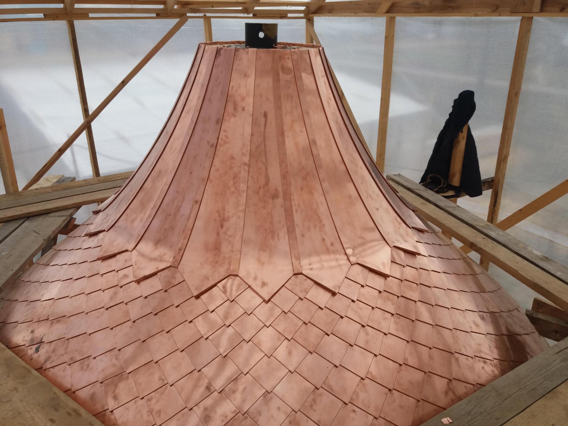 Hand-formed copper dome with standing seam panels and scalloped shingles under a wooden work frame