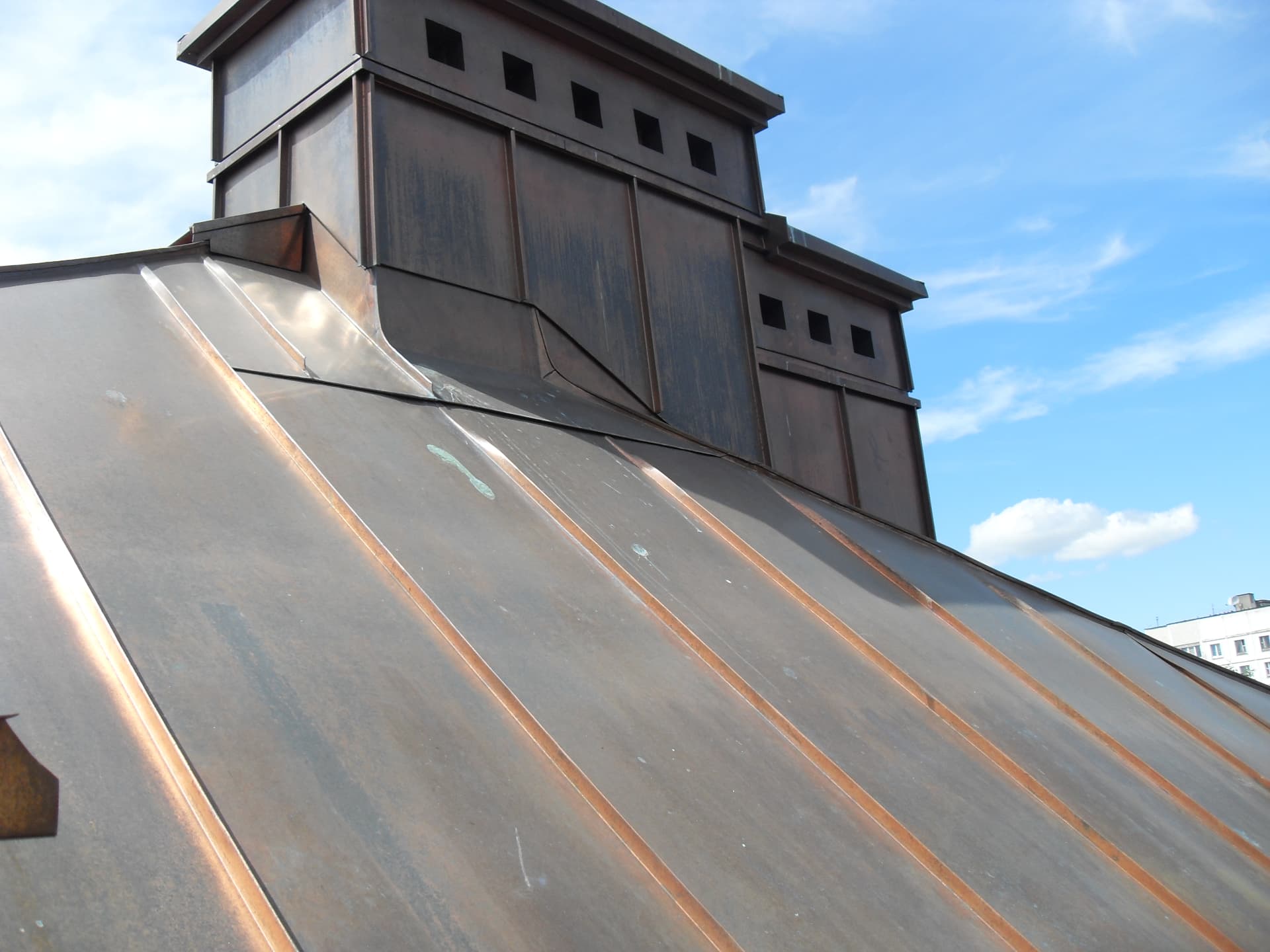 Hand-formed copper chimney cupola with ventilation slots on a standing seam copper roof